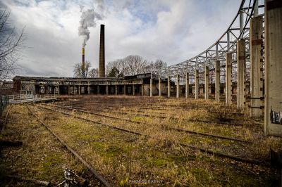Eine Bahnstrecke mit einer Fabrik im Hintergrund