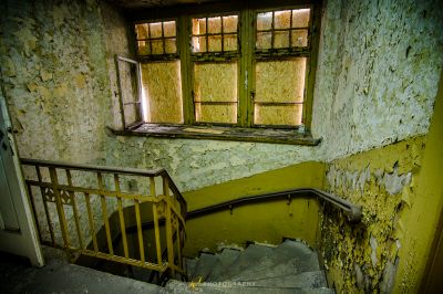 Ein Zimmer mit einem kaputten Fenster und einer Treppe