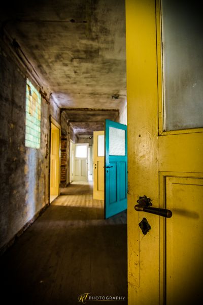 Ein langer Flur mit einer blauen Tür und gelben Wänden