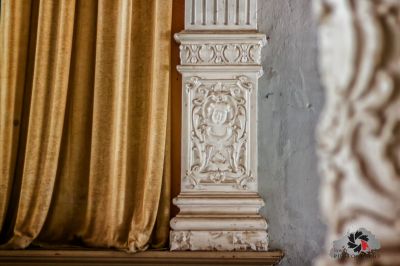 Eine weiße Säule mit einem goldenen Vorhang im Hintergrund