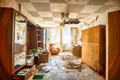 Ein Zimmer mit einer kaputten Decke und einem kaputten Kühlschrank