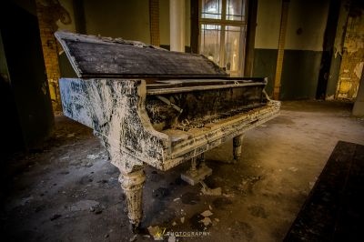 Ein Klavier in einem Zimmer mit einem zerbrochenen Fenster