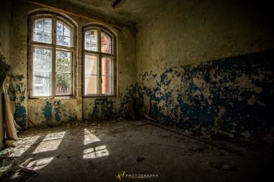 Ein Raum mit einem Fenster und einer Wand mit schälender Farbe