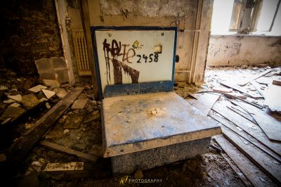 Ein kaputter Laptop sitzt in einem Raum mit einem Graffiti an der Wand