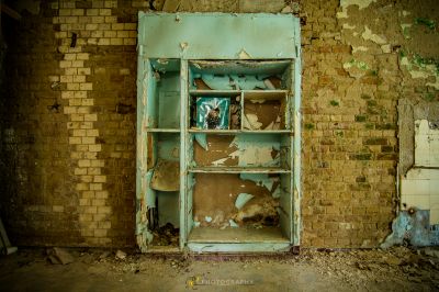 Ein gebrochener Kühlschrank in einem Raum mit einer Ziegelwand