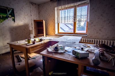 Ein chaotischer Schreibtisch in einem chaotischen Raum mit einem Fenster