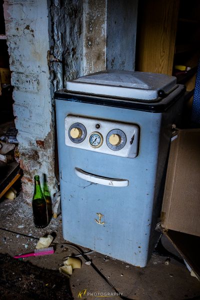 Ein kleiner Kühlschrank sitzt in einem schmutzigen Zimmer