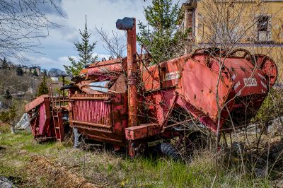 Ein roter LKW sitzt auf einem Feld neben einem Gebäude