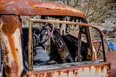 Ein verrostetes Auto sitzt in einem Schrottplatz