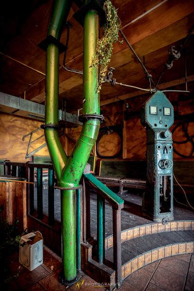 Ein grünes Rohr ist in einem Raum mit einem Ziegelboden