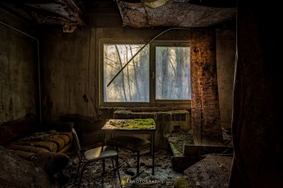 Ein Zimmer mit einem kaputten Fenster und einem Stuhl