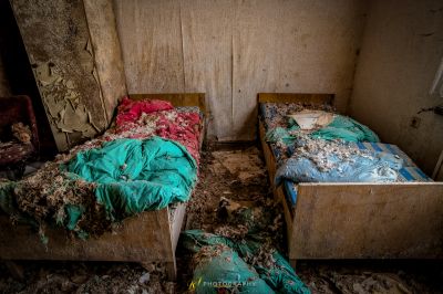 Ein schmutziges Zimmer mit zwei Betten und einem Haufen Müll