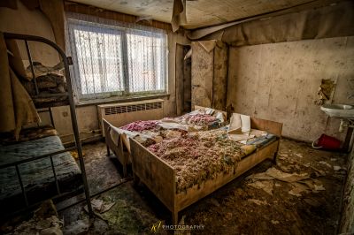 Ein chaotisches Bett in einem schmutzigen Zimmer mit einem Fenster