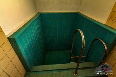 Ein grünes gefliestes Bad mit einem Metall-Handlauf