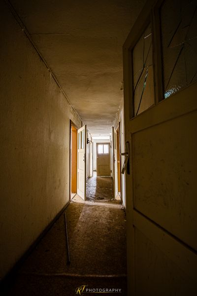 Einen langen Flur mit einer Tür und einem Fenster