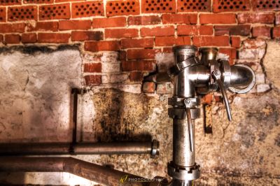 Ein Metall Wasserhahn mit einer Ziegelwand im Hintergrund