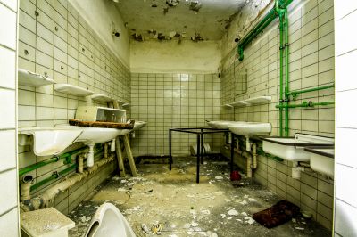 Ein Badezimmer mit einem gebrochenen Waschbecken und einer kaputten Toilette