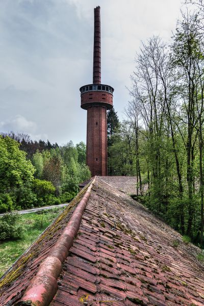 Ein Ziegelkamin auf einem Dach mit Bäumen im Hintergrund
