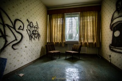 Ein Zimmer mit einem Stuhl und einem Fenster mit Graffiti darauf