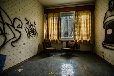 Ein Zimmer mit einem Stuhl und einem Fenster mit Graffiti darauf