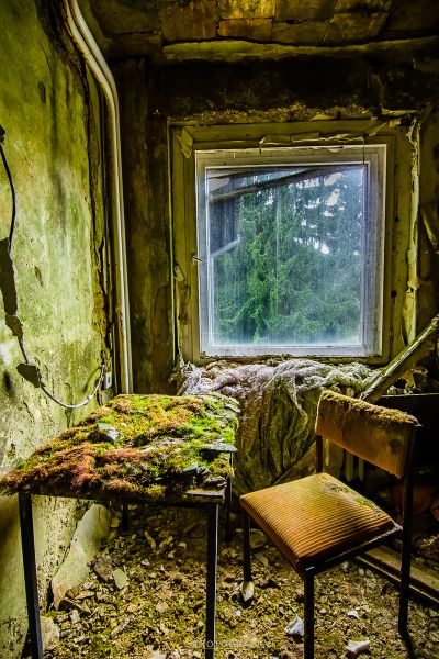 Ein Zimmer mit einem kaputten Fenster und einem Stuhl