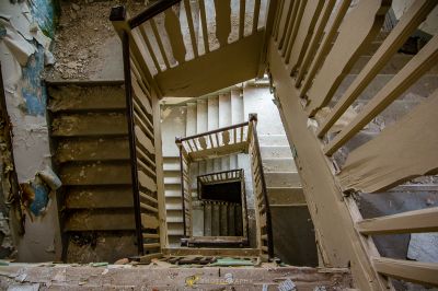 Eine Treppe in einem heruntergekommenen Haus mit einer kaputten Tür