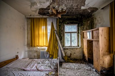 Ein chaotisches Schlafzimmer mit einem Bett und einem kaputten Fenster