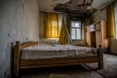 Ein Bett in einem Zimmer mit einem Fenster und einem Holzbettrahmen