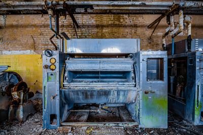 Eine große Maschine in einem schmutzigen Raum mit einer Ziegelwand