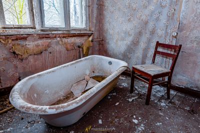 Eine Badewanne in einem schmutzigen Badezimmer mit Stuhl