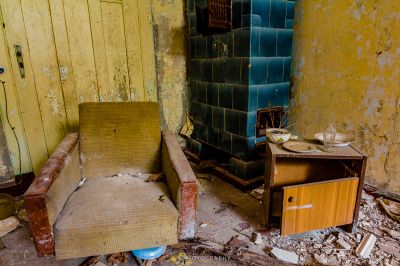 Ein schmutziges Zimmer mit einem gebrochenen Stuhl und einem gebrochenen Kühlschrank