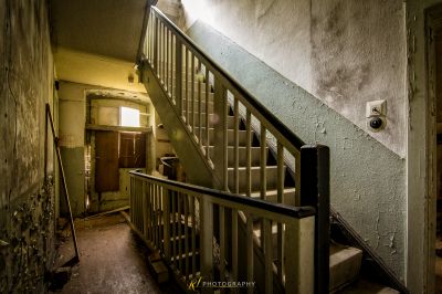 Eine Treppe in einem verlassenen Gebäude mit einem Licht, das durch das Fenster kommt