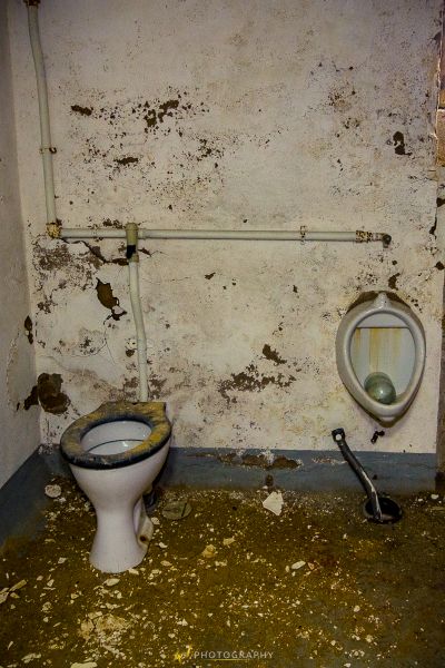 Ein schmutziges Badezimmer mit einer Toilette und einer kaputten Toilette