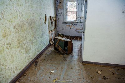 Ein Zimmer mit einem kaputten Fernseher und einem kaputten Fenster