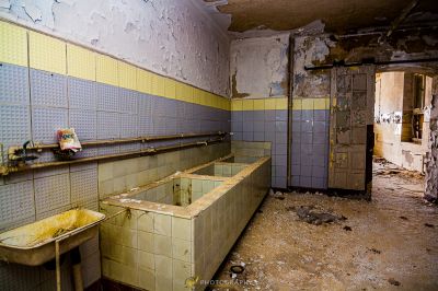 Ein schmutziges Badezimmer mit einem Waschbecken und einem zerbrochenen Spiegel