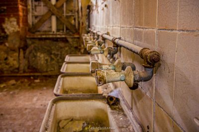 Eine Reihe von Waschbecken in einem schmutzigen Badezimmer