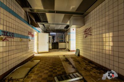 Ein schmutziges Zimmer mit einem gefliesten Boden und einer Wand mit Graffiti