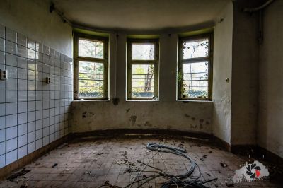 Ein Zimmer mit einem zerbrochenen Fenster und einem zerbrochenen Fliesenboden