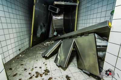 Ein schmutziges Badezimmer mit einem Waschbecken und einem kaputten Kühlschrank