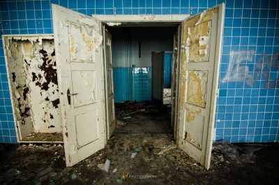 Ein Zimmer mit einer zerbrochenen Tür und einer Wand aus blauen Fliesen