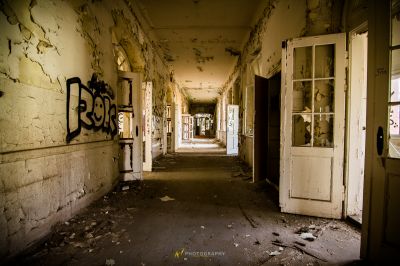 Einen Flur mit einer Tür und Graffiti an den Wänden