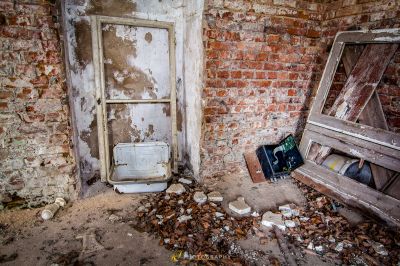 Eine kaputte Toilette, die in einem Zimmer mit einer kaputten Tür sitzt