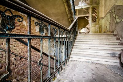 Eine Treppe mit einem kaputten Geländer und einer kaputten Tür