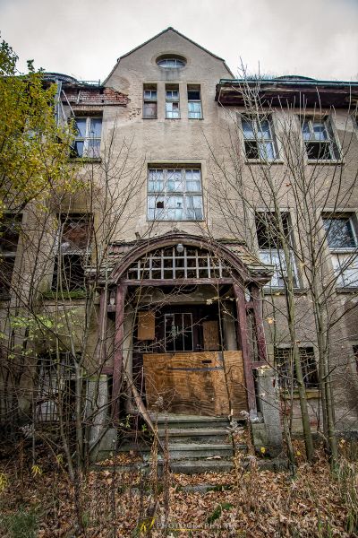 Ein altes Haus mit einer verengten Tür und einem Baum vorn