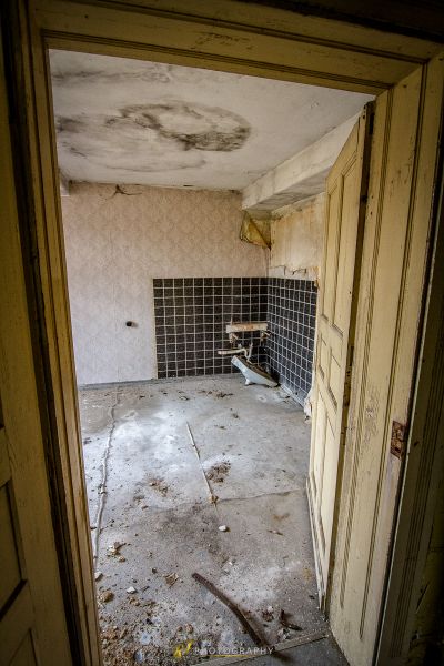 Ein schmutziges Badezimmer mit einer kaputten Toilette und einer kaputten Tür