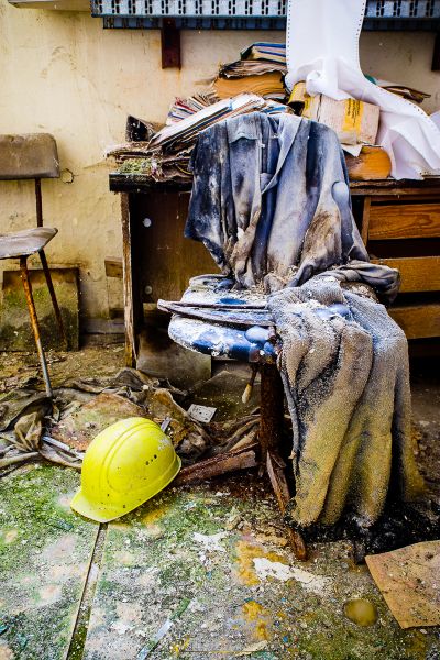 Ein schmutziges Zimmer mit einem gebrochenen Stuhl und einem gelben Helm