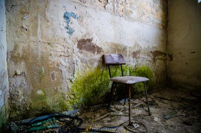 Ein Stuhl in einem Raum mit einer Wand, die mit Graffiti bedeckt ist