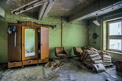 Ein Zimmer mit einem gebrochenen Spiegel und einem Stuhl