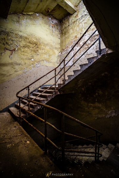 Eine Treppe in einem verlassenen Gebäude mit einem gebrochenen Handlauf