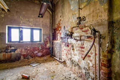 Ein schmutziges Badezimmer mit einem gebrochenen Waschbecken und einem Fenster